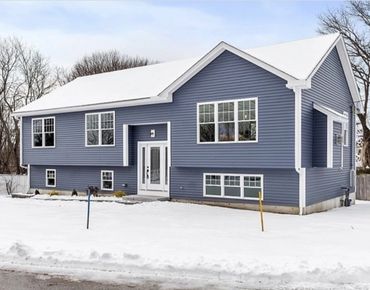 Blue house with white trim surrounded by snow in winter.