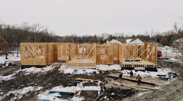 Wooden framework of a house under construction in a snowy area.