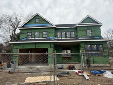 Two-story house under construction with green ZIP System sheathing and multiple windows.