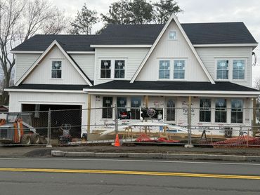 A large house under construction with fencing and construction equipment in front.