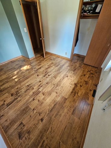 Empty room with wooden flooring and open closet door.