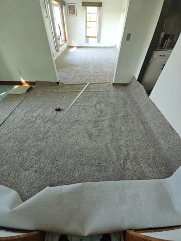 Partially installed carpet with measuring tools in a home interior.