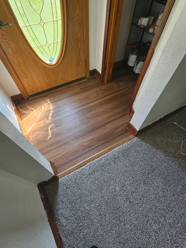 Sunlit entryway with wood flooring and carpet transition.
