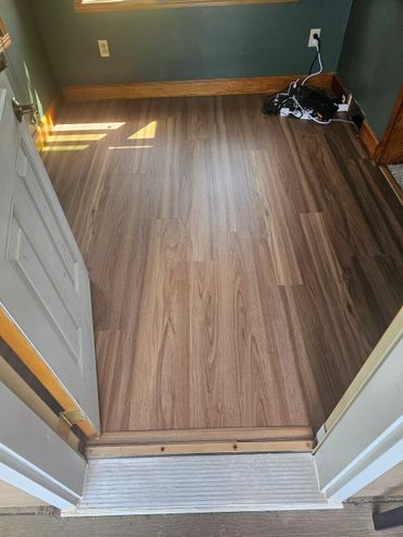 Empty room with new wood flooring and green walls.