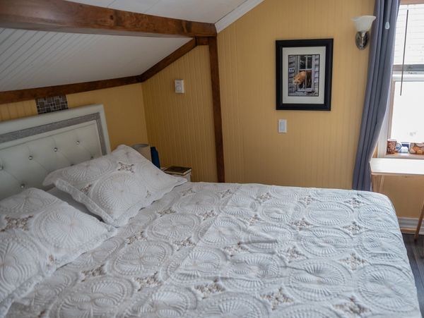 Cozy bedroom with a white quilted bedspread and framed artwork on yellow walls.