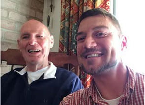 Two men smiling indoors.