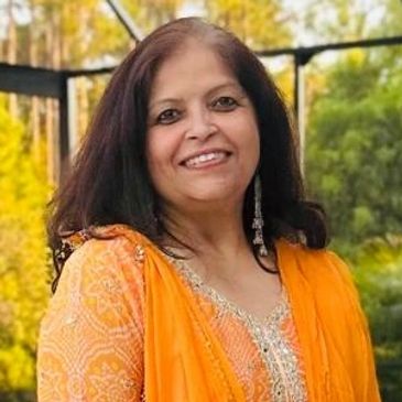 Smiling woman in a vibrant orange traditional outfit outdoors.