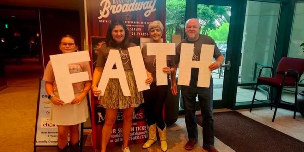 Four people holding large letters spelling FAITH indoors.