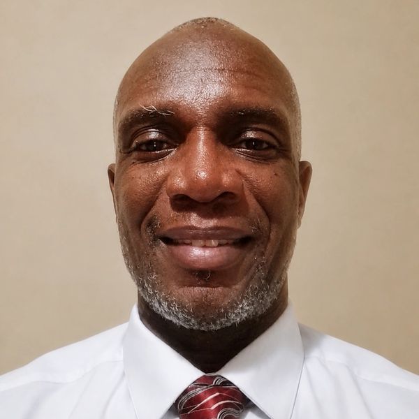 Smiling man in a white shirt and red striped tie.