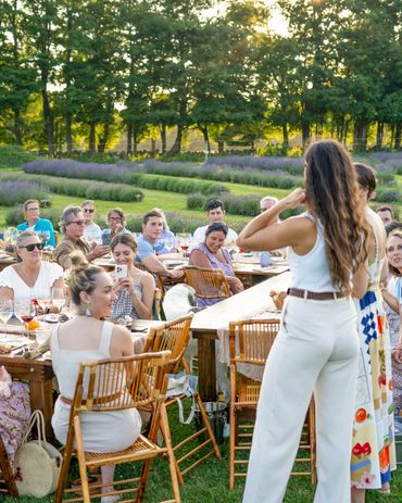 People enjoying an outdoor gathering at sunset with lavender fields in the background.