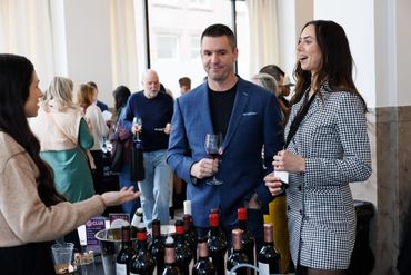 People enjoying a wine tasting event with bottles and glasses on display.