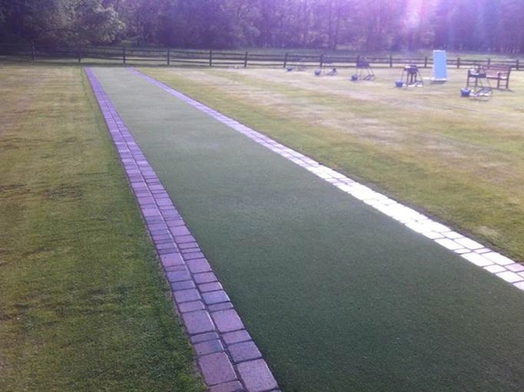 Long green cricket pitch on grassy field.