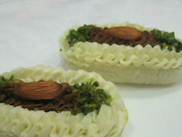 Two intricately decorated Indian sweets with almond and pistachio toppings.