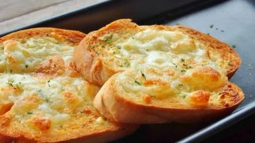Three slices of garlic bread topped with melted cheese and herbs.