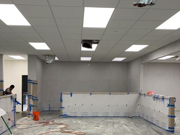 An indoor area under construction with protective coverings and tools scattered.