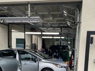 A silver car being cleaned at a car wash station with doors open.