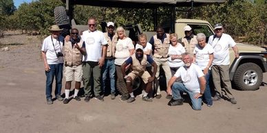 Group photo of people posing outdoors near a safari jeep.