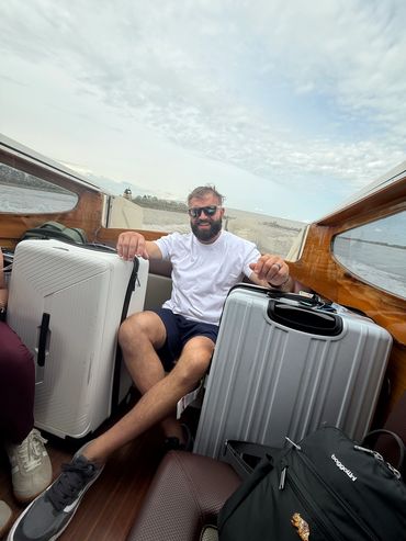 Man smiling with luggage on a boat ride.
