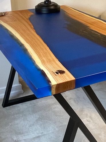 Wood and blue resin desk with black metal legs and a black lamp.