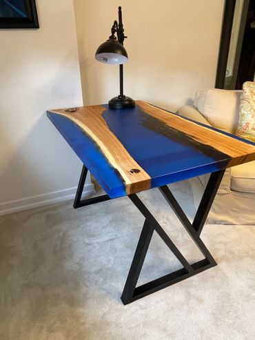 Wood and blue resin desk with black metal legs and a black lamp.