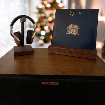Wooden headphone stand and Queen Greatest Hits II album on a Klipsch speaker with Christmas lights in background.