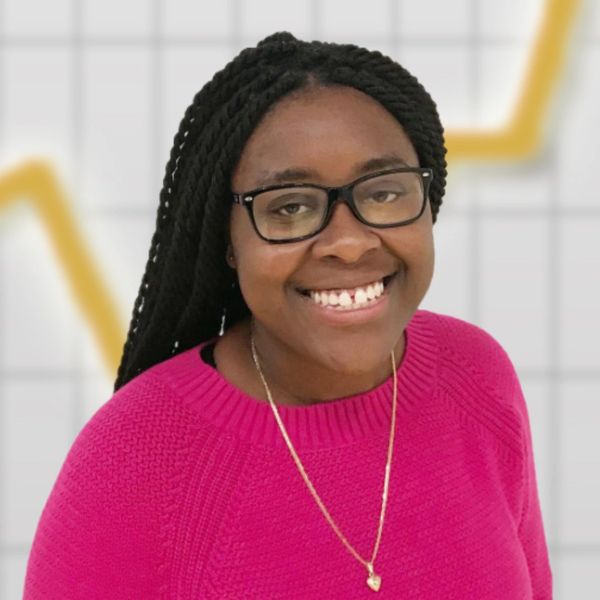 Smiling woman with glasses and braided hair in a pink sweater.