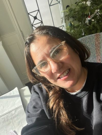 Woman wearing glasses smiling in natural light.
