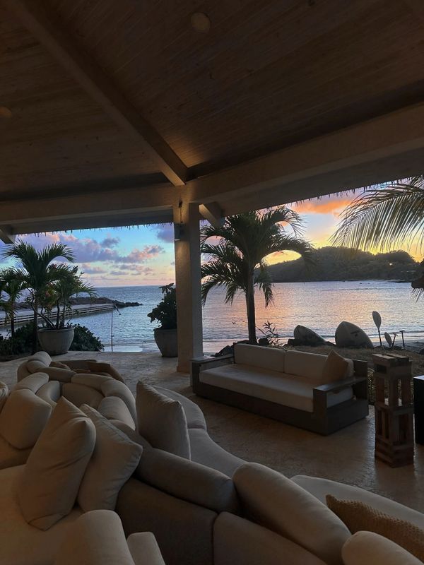Cozy outdoor seating area overlooking a serene ocean at sunset.
