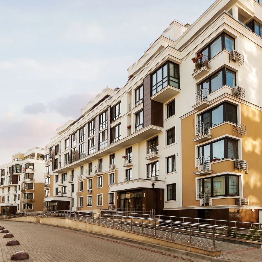 Modern residential apartment buildings with large windows and balconies under a clear sky.