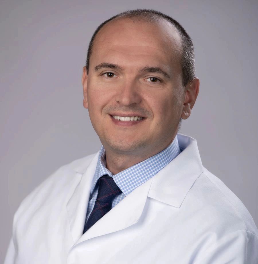 Smiling man in a white medical coat with a tie.