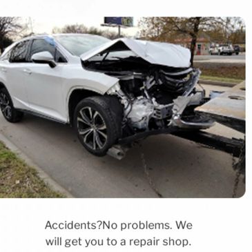 Damaged white car being towed to a repair shop after an accident.