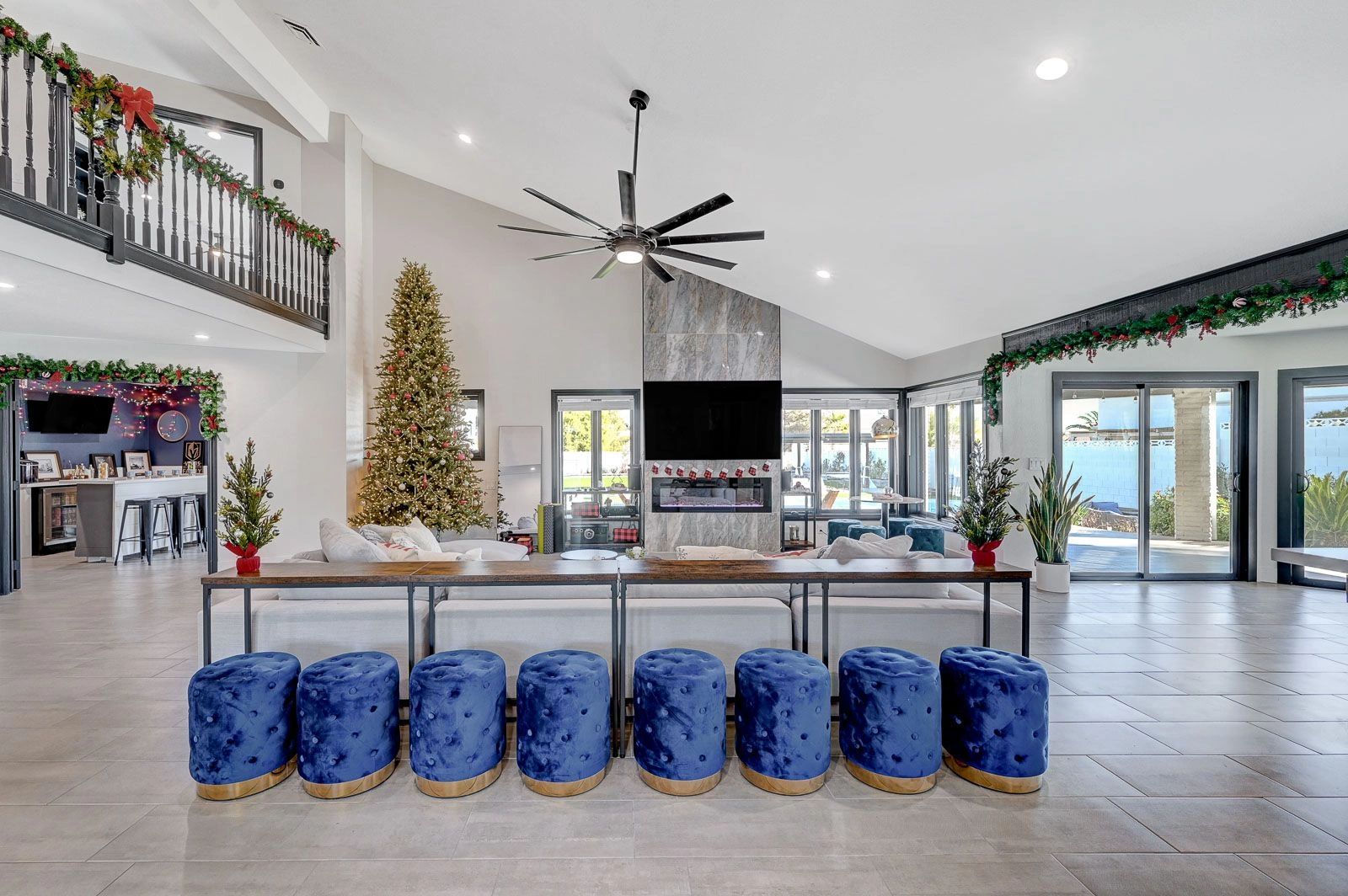 Beautiful large white meeting and event venue with blue stools and black ceiling fan.