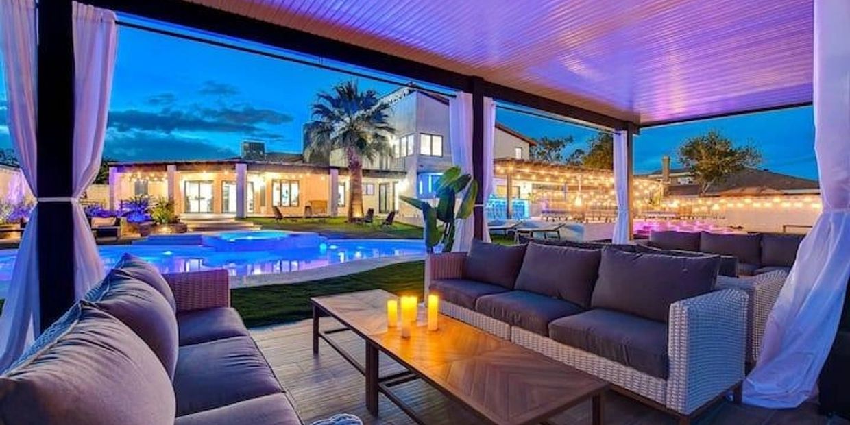 Covered patio seating at twilight overlooking blue pool.