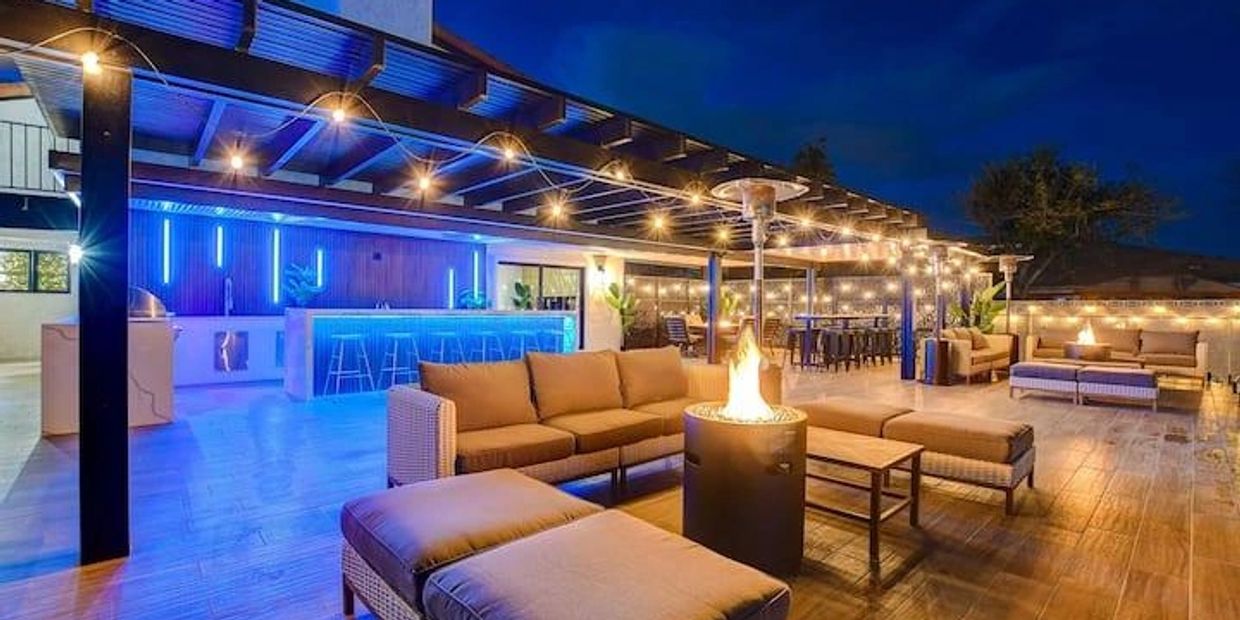Vibrant night blue and gold lighting on patio with firepit and furniture.