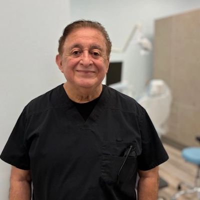 Smiling male healthcare professional in black scrubs in a medical office.