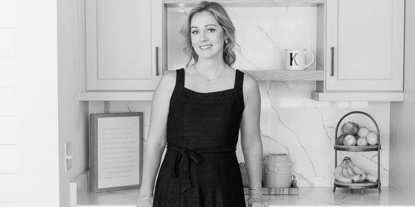Woman in a black dress and pink heels standing in a modern kitchen.