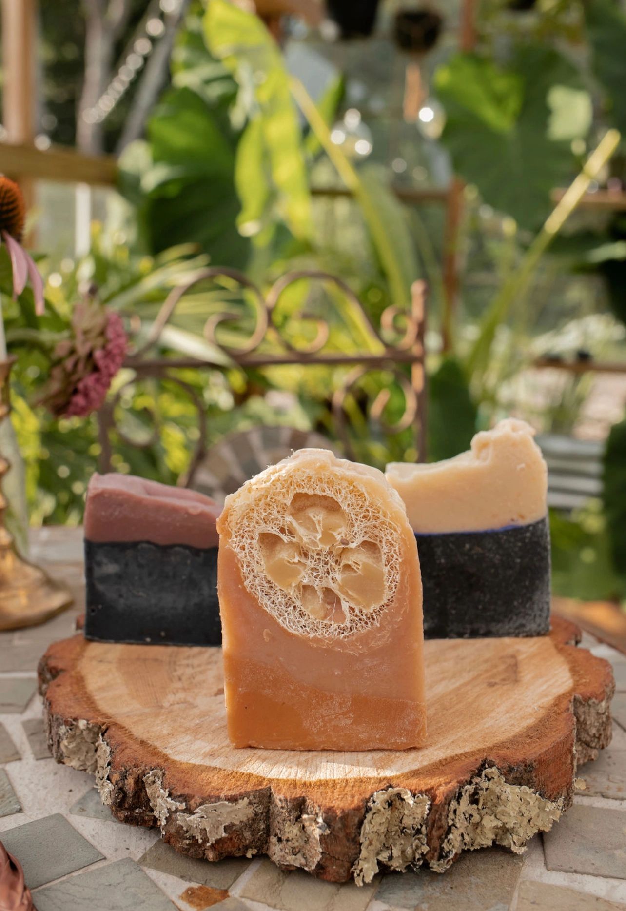 3 different goat milk soaps on display atop a wooden circle in the greenhouse 