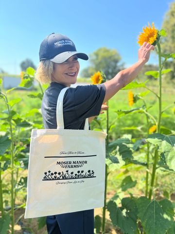 Woman with tote bag picking a sunflower