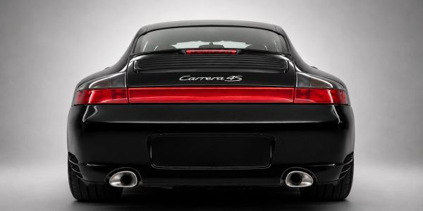 Rear view of a sleek black Porsche Carrera 4S with distinct red tail light.