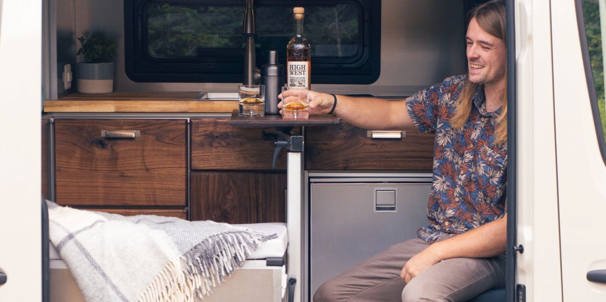 Man enjoying a drink inside a cozy camper van.