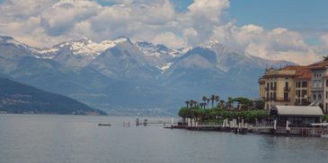 Scenic lakeside view with snow-capped mountains and buildings along the shore.
