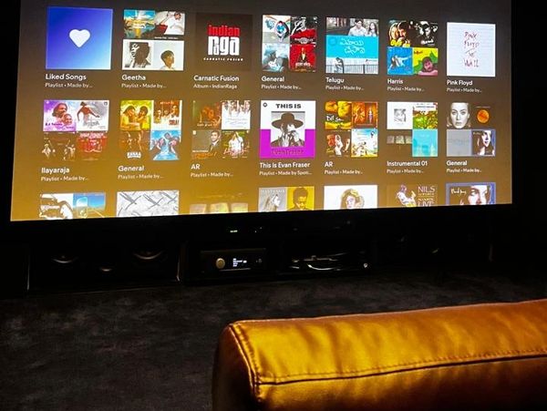 Home theater setup showing music playlists on a large screen.