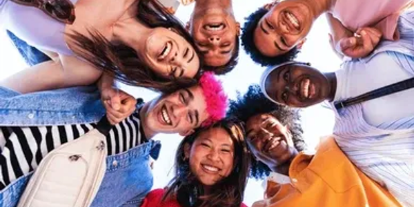 Group of happy friends smiling in a circle looking down.