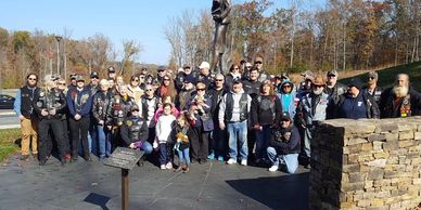 Group of bikers posing outdoors next to a statue.