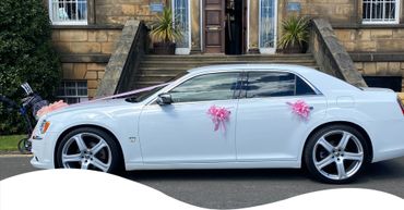 A modern white Chevrolet limousine saloon car in pink wedding ribbons