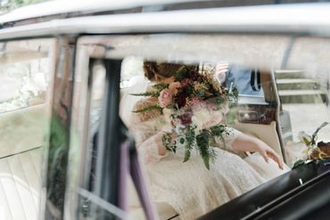 A photo of a bride riding in the back of a classic Daimler DS420 limousine wedding car