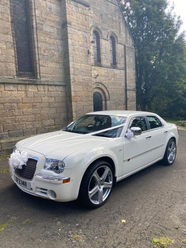 A modern white Chevrolet saloon car limousine in white wedding ribbons