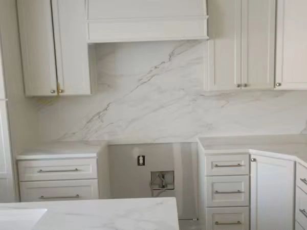 Empty white kitchen cabinets and marble countertops.