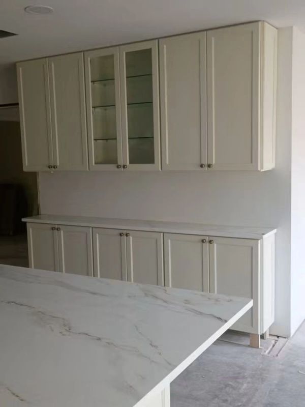 White kitchen cabinets with marble countertop.
