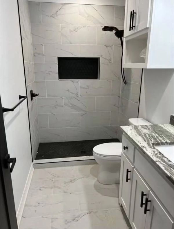 Modern bathroom with marble tiles and black accents.